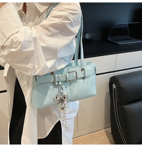 Dettaglio della borsa baguette azzurra in pelle con ciondolo a fiocco e fibbia in argento