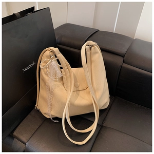 Detalle del bolso de cuero crema con cinta de encaje y colgante de perlas finas