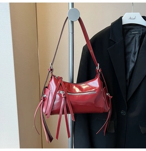 Detalle de bolso de hombro en charol rojo con cremalleras y flecos decorativos