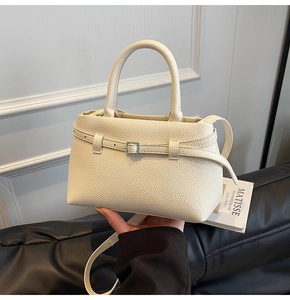 Detail of beige lychee grain leather tote bag with metal buckle and shoulder strap