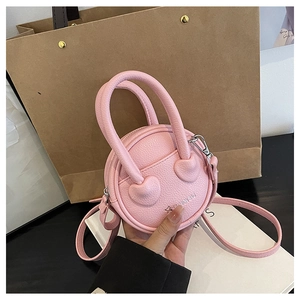 Détail d'un mini sac à main rond rose avec texture litchi et poignée en forme de cœur