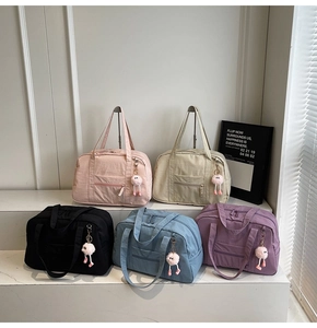 Detailed display of five colorful canvas travel bags with front pockets and plush charms
