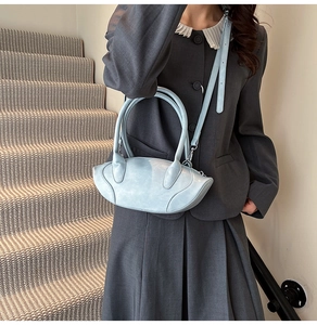 Detail view of light blue leather handbag with silver hardware on a professional model