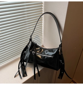 Detalle del bolso de hombro en cuero brillante negro con herrajes plateados y flecos