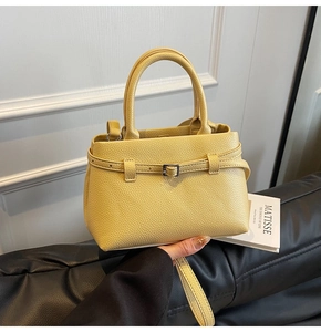 Close-up of bright yellow litchi grain leather tote bag with elegant buckle detail