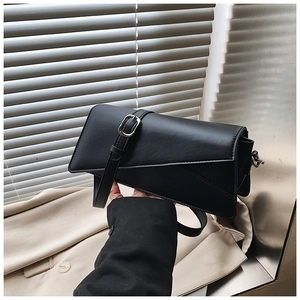 Detail of a black geometric crossbody bag with silver buckle and matte finish