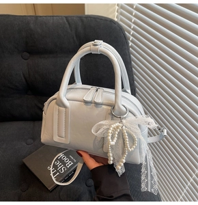 Detail of light blue Boston bag featuring pearl lace charm and smooth glossy leather finish