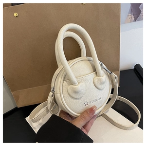 Gros plan du sac à bandoulière rond blanc avec texture litchi et logo étoilé