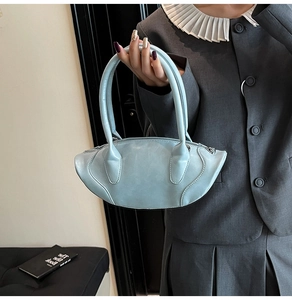 Detail of light blue football-shaped leather handbag with double handles and side stitching