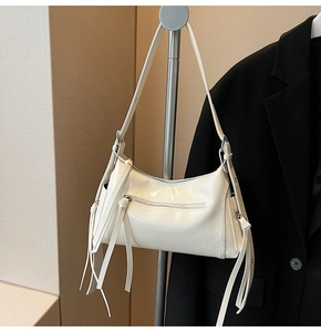 Detalle del bolso de hombro blanco con cremalleras plateadas y flecos largos de cuero