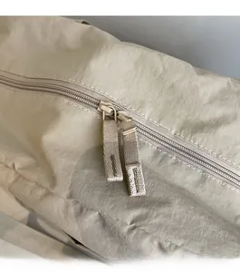 Macro detail of the smooth dual zipper system with long webbing pullers on canvas travel bag