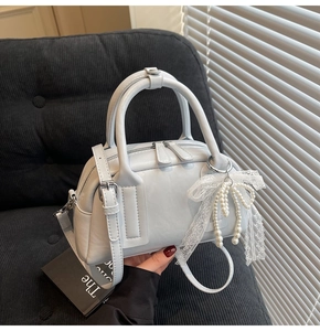 Detail of light blue Boston bag with lace bow and pearl charm on corduroy