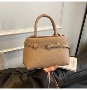 Detail of khaki bucket bag showing litchi grain texture and elegant side buckle strap