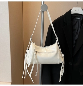 Detalle de bolso de hombro en charol blanco crema con flecos y cremalleras plateadas