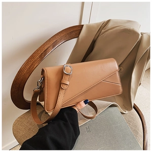 Detail of caramel faux leather bag on wooden chair with silver buckle and stitch texture