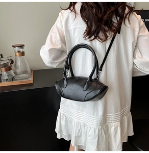 Detail of a black leather handbag featuring dual handles and smooth metal zipper closure
