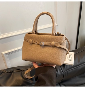 Detail of apricot bucket bag featuring lychee grain leather and metal buckle closure