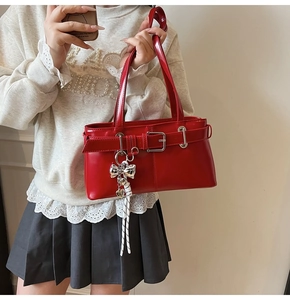 Dettaglio della borsa in pelle verniciata rossa con pendente a farfalla e cuore