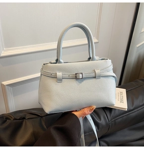 Detail of light blue bucket bag showing lychee pattern texture and metal buckle strap