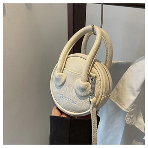 Détail du mini sac à main rond crème avec texture en cuir et logo de mode stylé