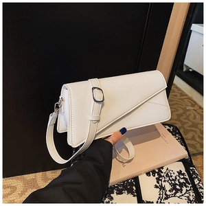 Close-up of white glossy leather handbag with asymmetrical flap and silver buckle detail