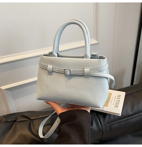 Detailed close-up of light blue lychee pattern leather handbag with metal buckle and strap
