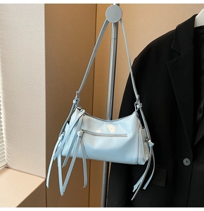 Detalle de bolso bandolera azul claro brillante con flecos y cremallera plateada