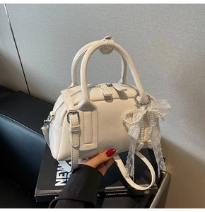 Detail of cream-white Boston bag with matte PU leather, silver hardware, and lace bow charm