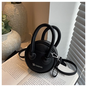 Gros plan du mini sac rond noir en cuir avec fermeture éclair et bandoulière amovible