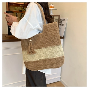 Detail of color-block straw tote bag featuring wooden beads and long tassel charm decoration