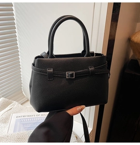 Close-up of black lychee-textured leather handbag with decorative silver buckle