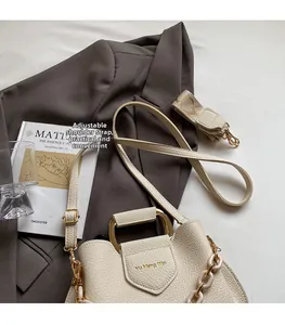 Detail of beige lychee textured leather bucket bag with adjustable strap on a blazer
