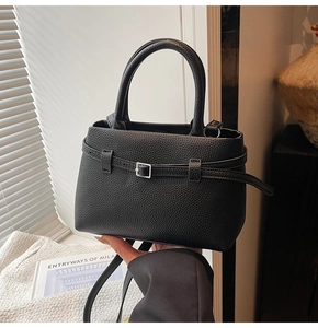 Detail of black pebbled leather texture on bucket bag with silver buckle and handle