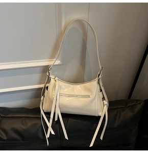 Detalle del bolso de hombro crema con acabado brillante y elegantes borlas de cuero