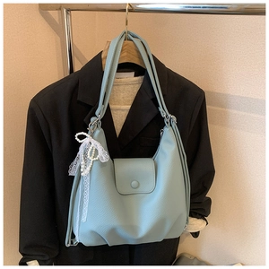 Primer plano de bolso tote azul claro con textura de lichi y colgante de perlas y encaje