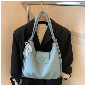 Detalle del bolso azul claro con patrón de lichi y colgante de perlas y encaje