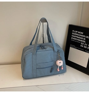 Close-up of deep blue canvas travel bag with front zipper pocket and plush pink charm