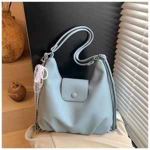 Detalle del bolso tote azul claro en cuero granulado con adorno de perlas