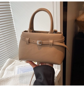 Detailed close-up of beige lychee grain leather handbag with silver buckle decoration