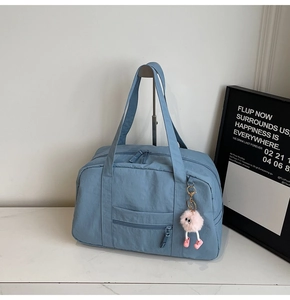 Detail of blue canvas travel bag featuring smooth dual zippers and a cute plush charm