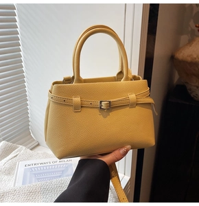 Detail of yellow lychee grain leather tote bag showing metallic buckle and handle