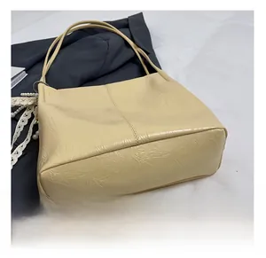 Détail du sac cabas beige avec texture cuir plissé et pendentif en perles et dentelle