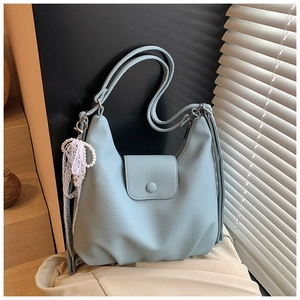 Detail of light blue pebbled leather tote with pearl lace charm and magnetic flap closure