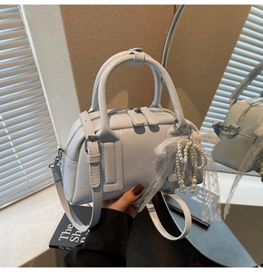 Detail of light blue glossy leather handbag with pearl chain and lace bow decoration