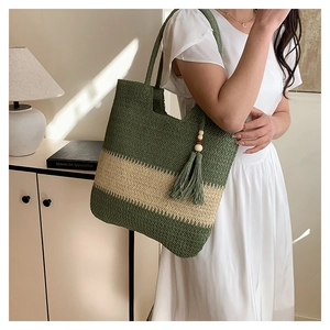 Detail of green and beige woven tote bag with fringe tassel and wooden beads