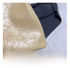 Détail macro de la texture en cuir plissé beige et coutures fines du sac fourre-tout