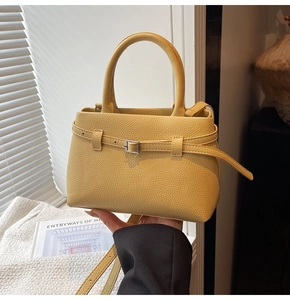 Macro view of yellow litchi grain texture and decorative belt buckle on the bucket handbag