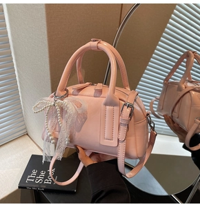 Detail of pink patent leather handbag with pearl lace bow and adjustable strap