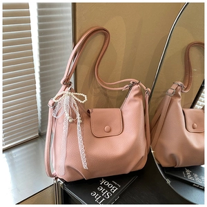 Detalle de textura de bolso hobo rosa con colgante de perlas y lazo de encaje