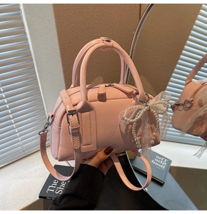 Detail of pink Boston bag with large pearl bow pendant and elegant lace trim detail